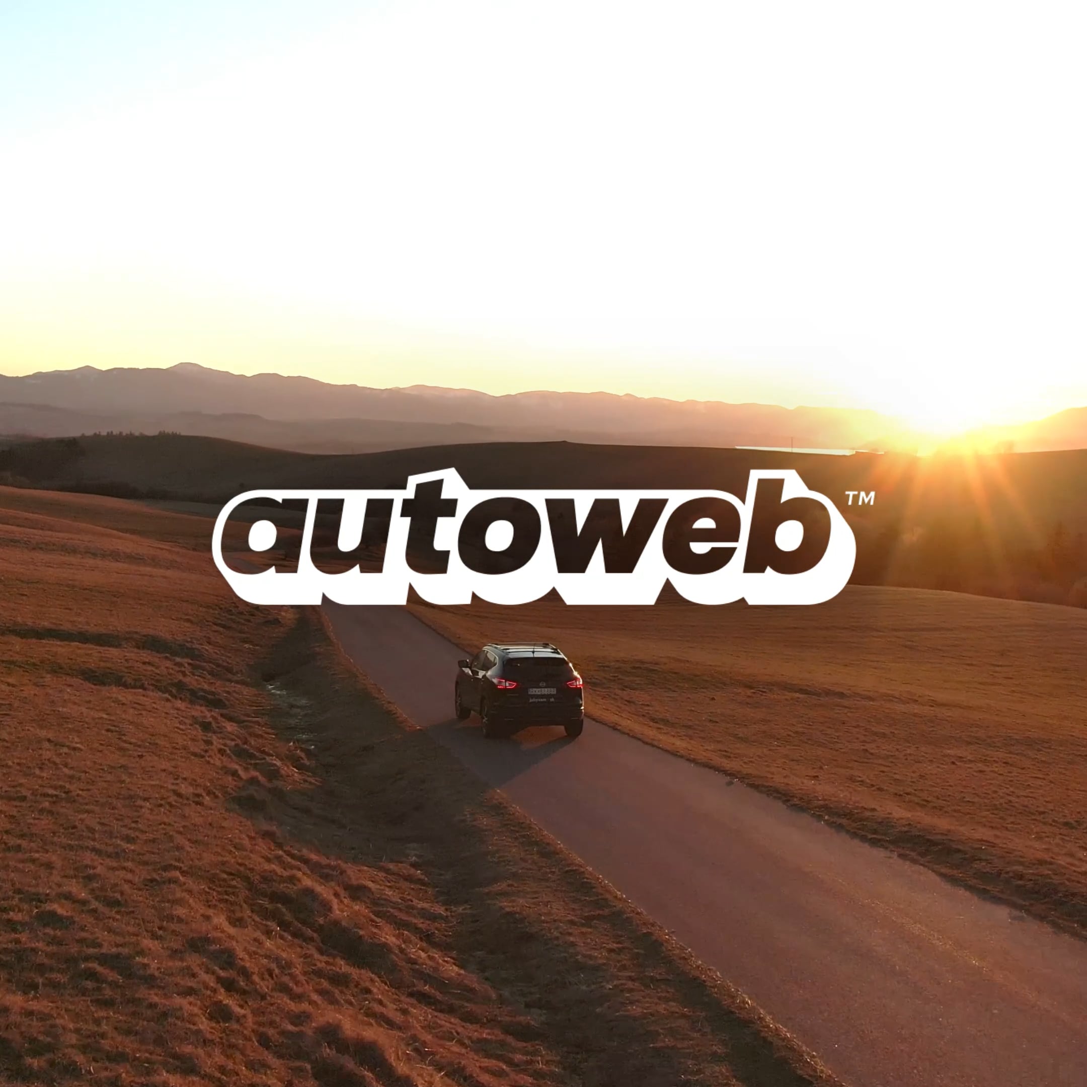 Autoweb (Mobile): Car driving on a winding road at sunset with mountains in the background.