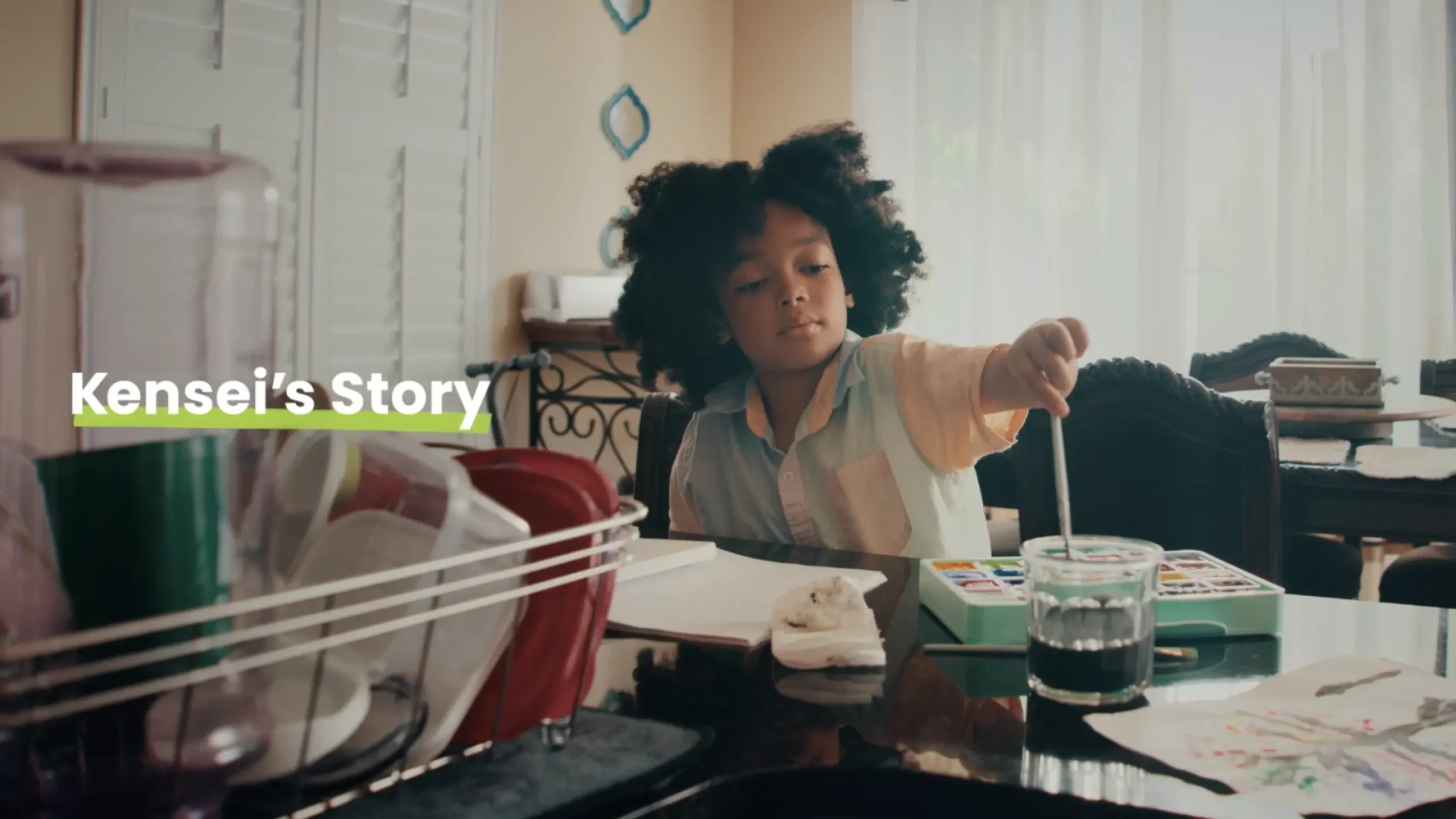 Young boy painting at a table, "Kensei's Story" text overlay