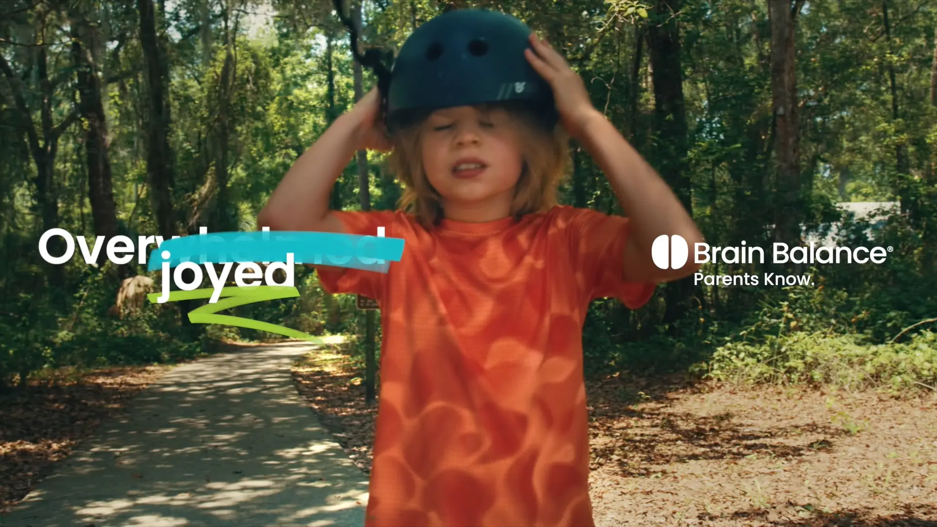 Boy putting on a helmet, ready for Brain Balance activities. Text: Overjoyed.