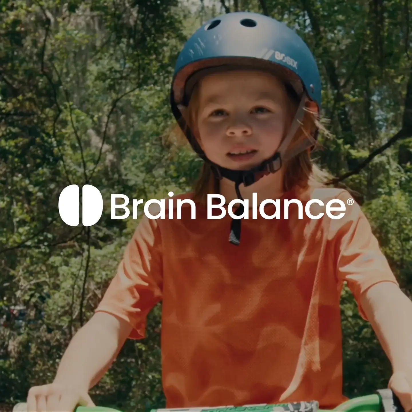 Child with helmet riding a bike, Brain Balance logo visible.