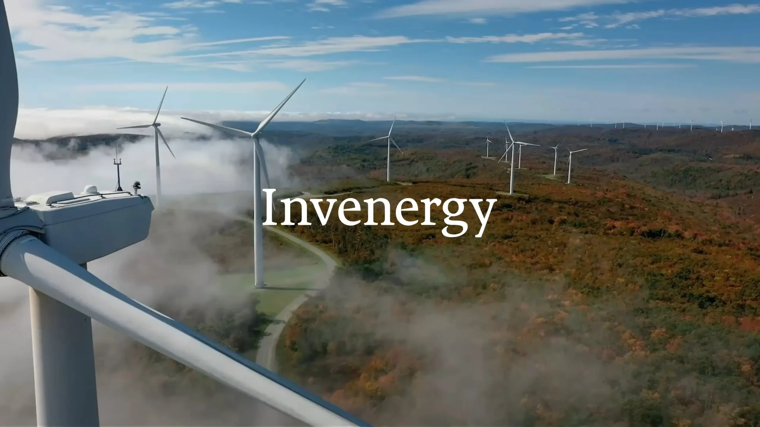 Invenergy wind turbines on a mountain ridge with low-lying clouds.