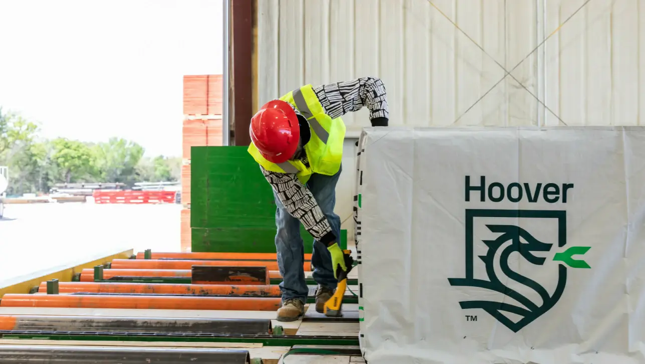Worker inspecting Hoover-branded building materials at a construction site.