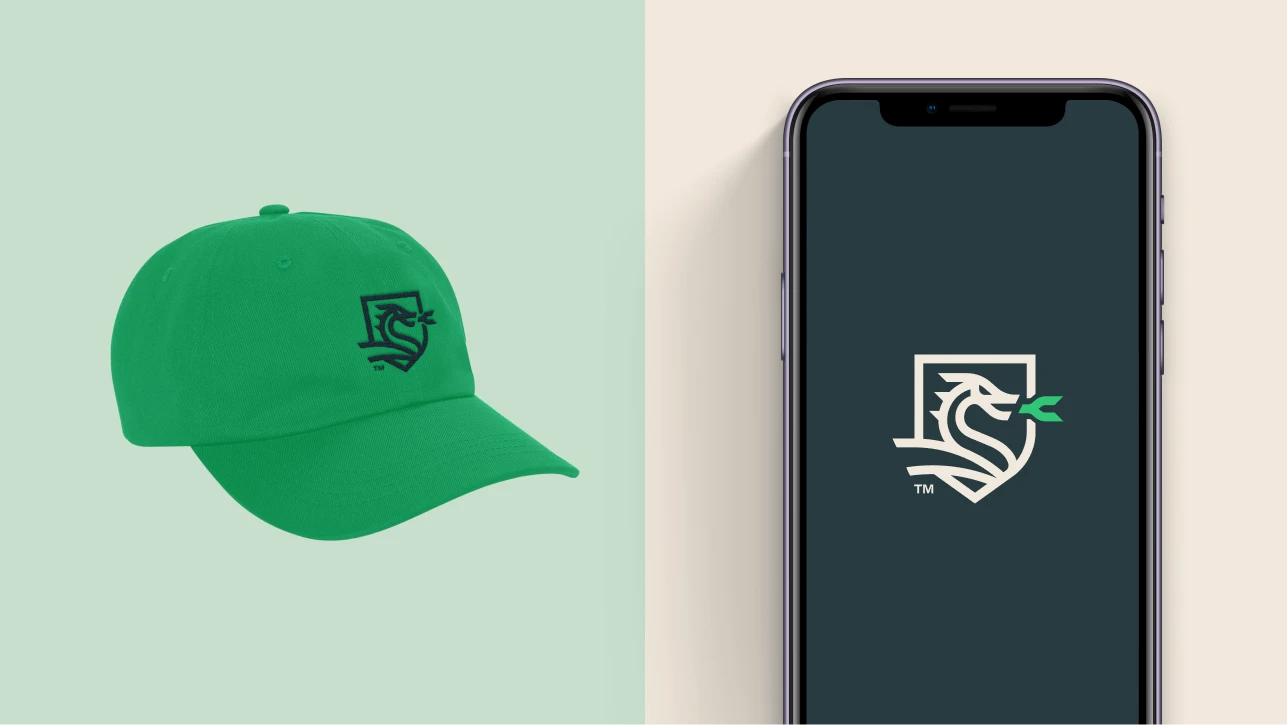 Green baseball cap with dragon logo next to phone with logo.