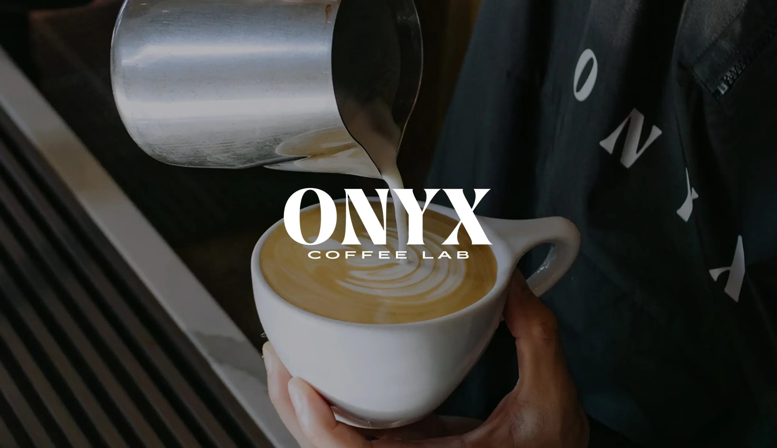 Latte art being poured at Onyx Coffee Lab. Text: Onyx Coffee Lab